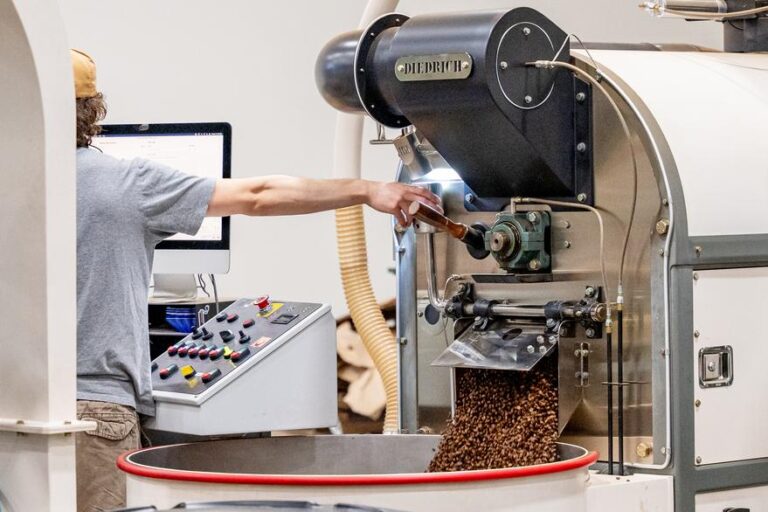 roasted coffee pours out of a machine.
